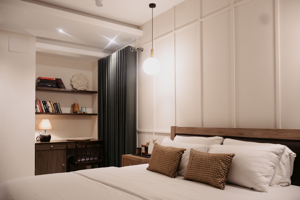 Primary bedroom with panelled walls, green curtains and warm pendant light