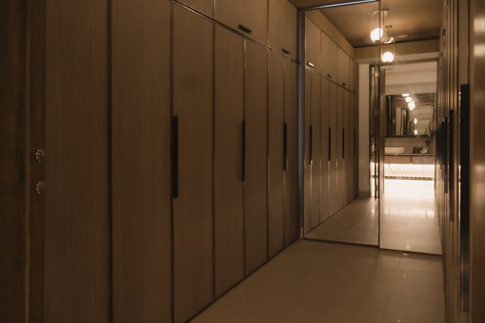 Long walk-in closet lined with timber cabinetry