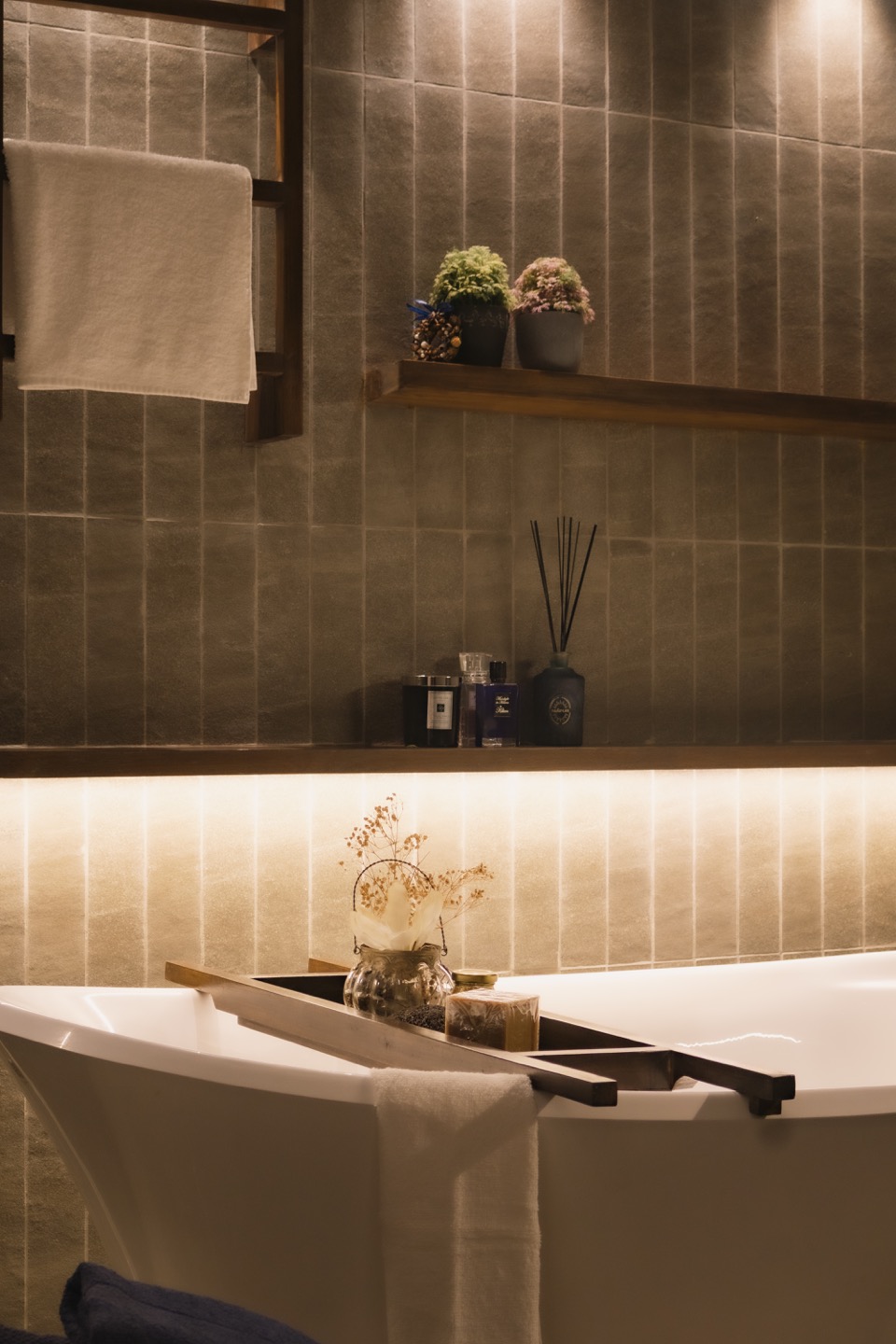 Freestanding bath beneath a softly illuminated ledge