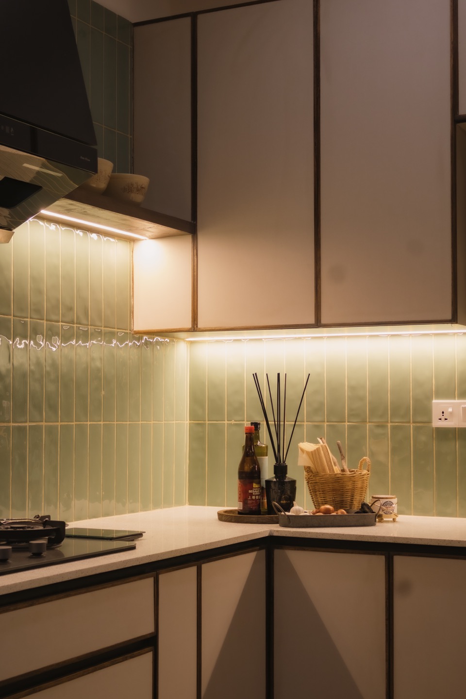 Vertical detail of sage tiles and pale kitchen cabinetry