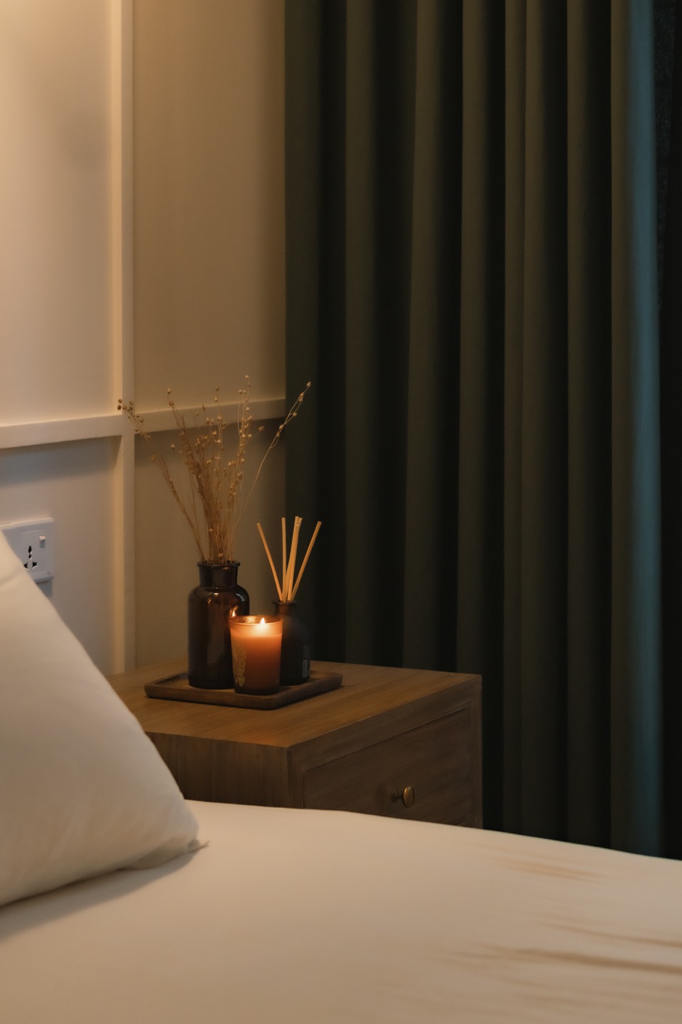 Bedside table, pendant light and deep green curtain