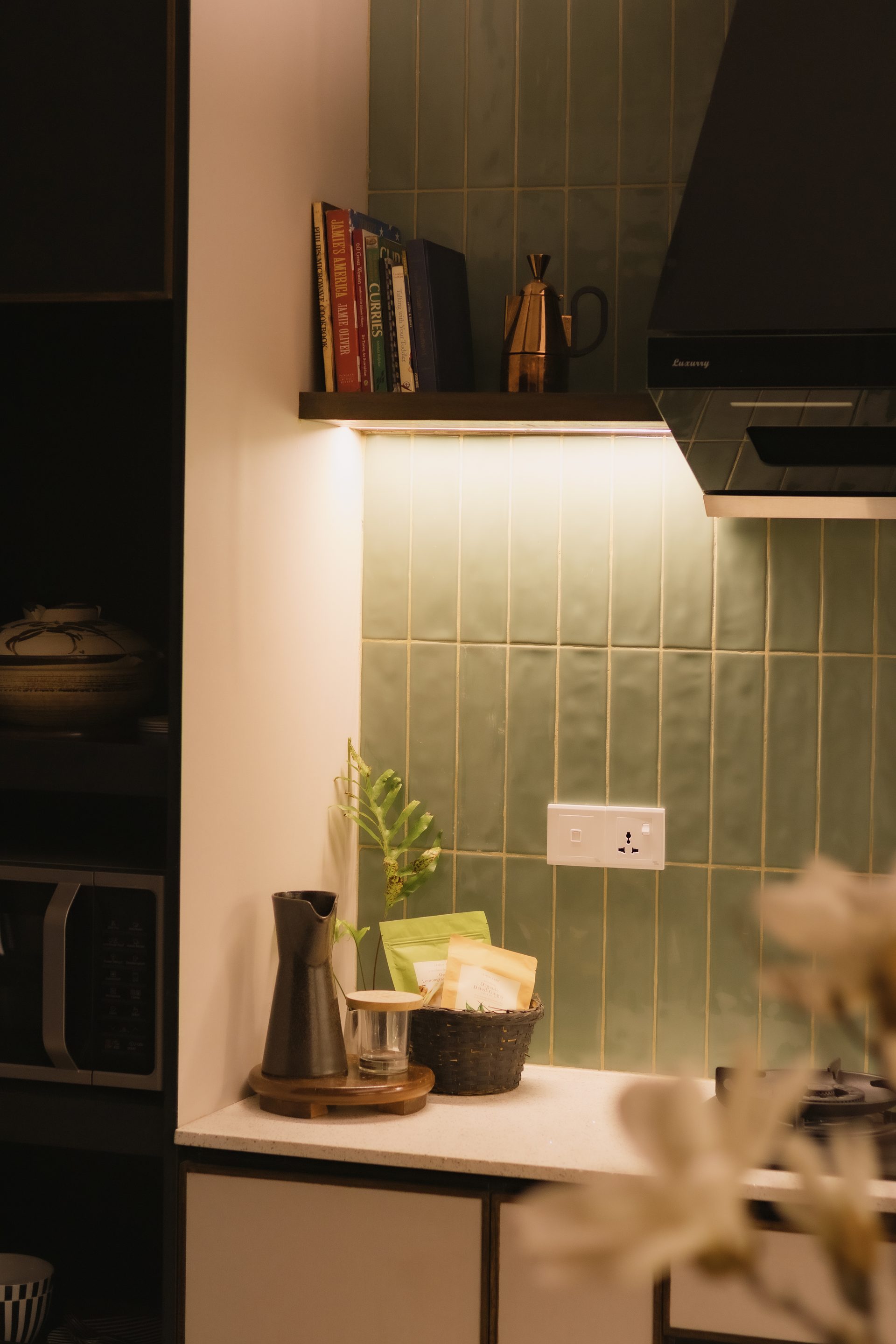 Close architectural detail of the sage green kitchen tile and pale cabinetry