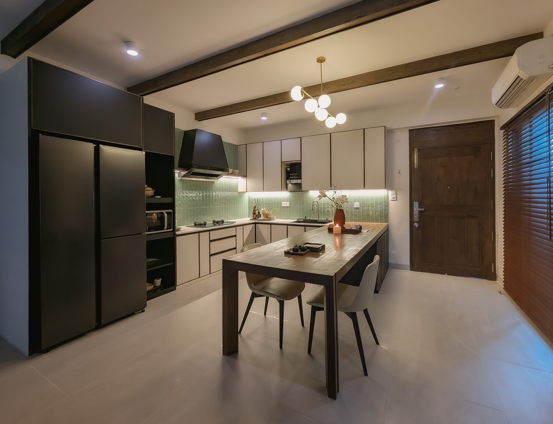 Long view through the kitchen showing charcoal cabinetry, pale worktops and timber beams