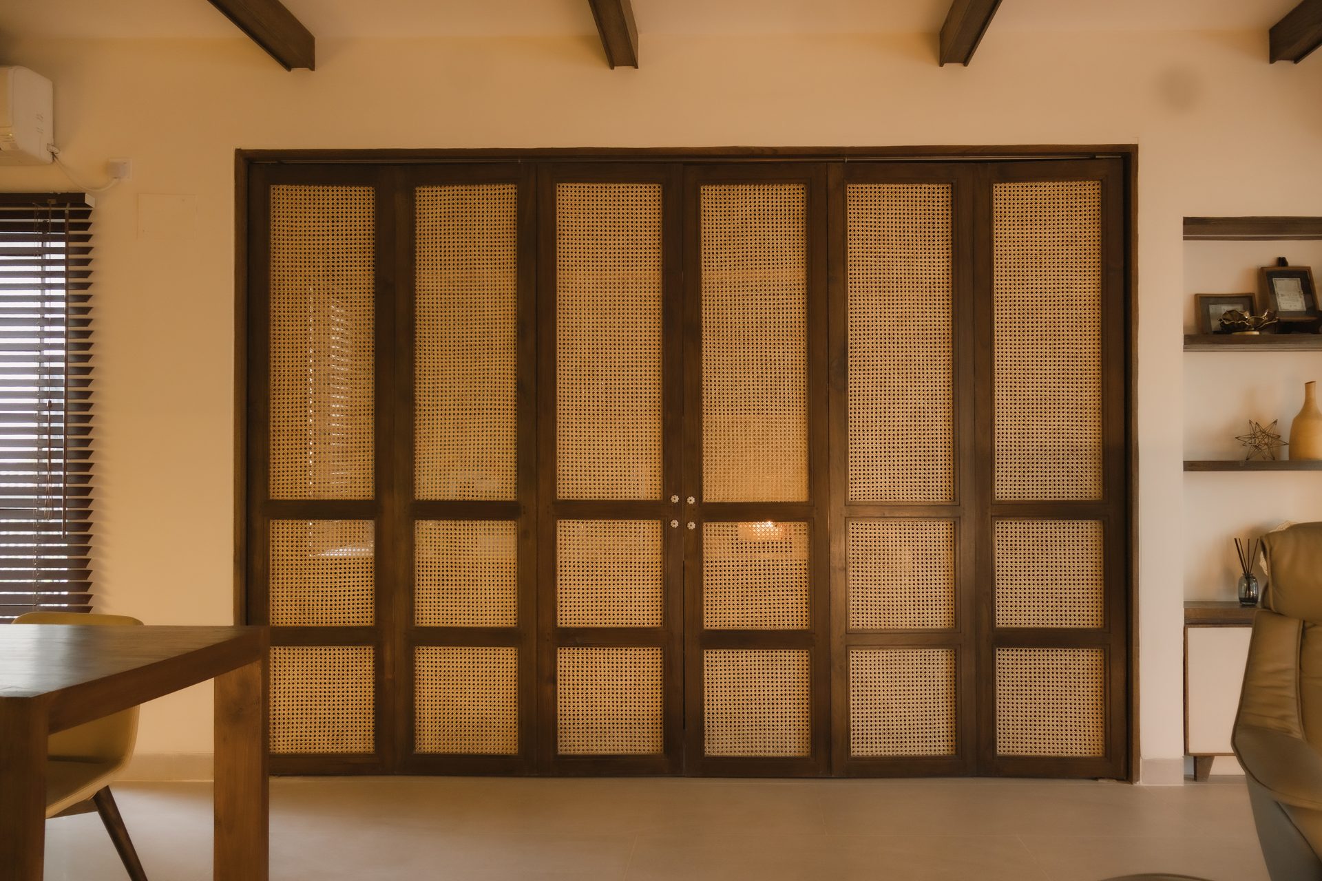 Laundry fully concealed behind a wall of dark timber and woven rattan doors