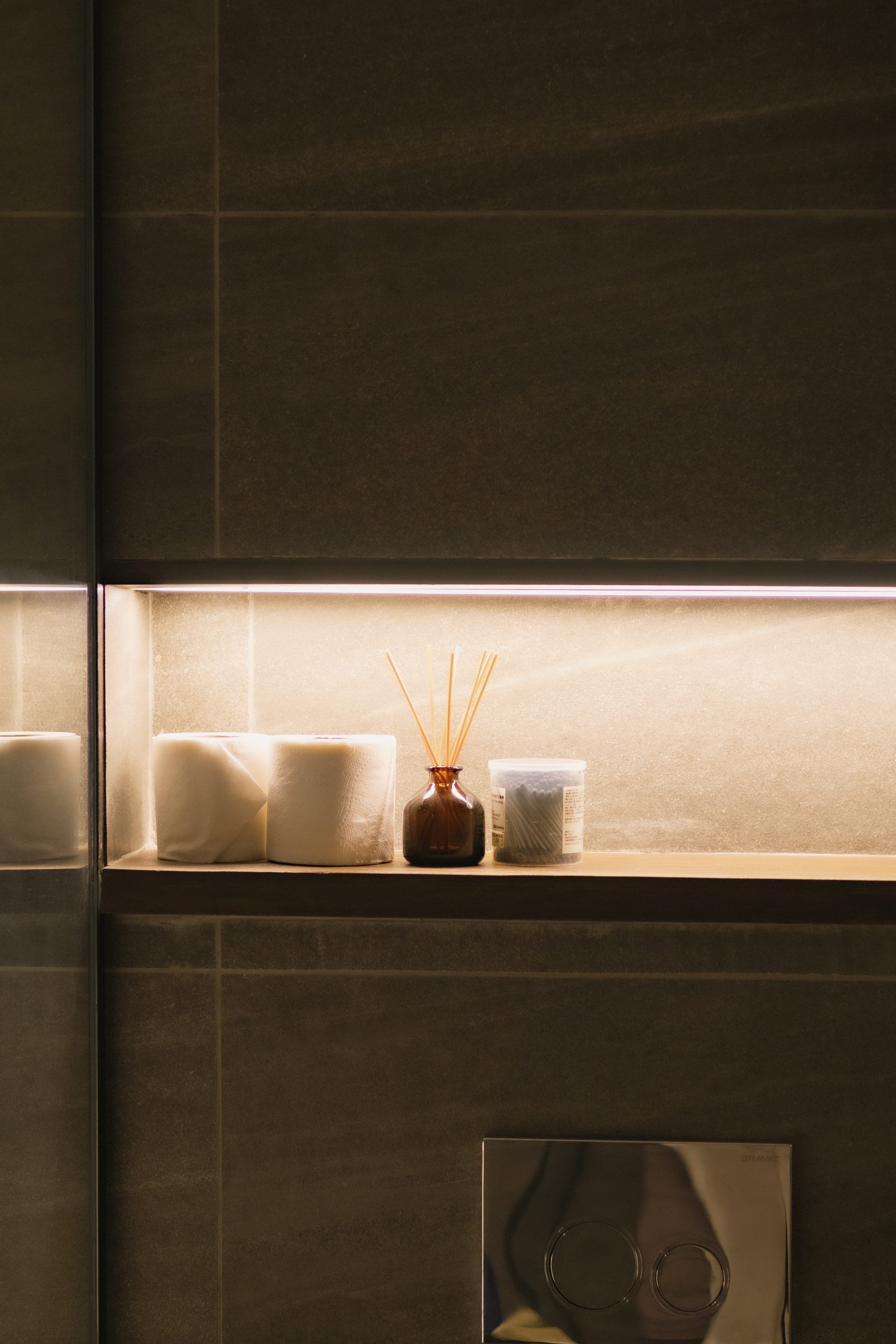 Folded towels and amber bottles arranged on an illuminated bathroom ledge