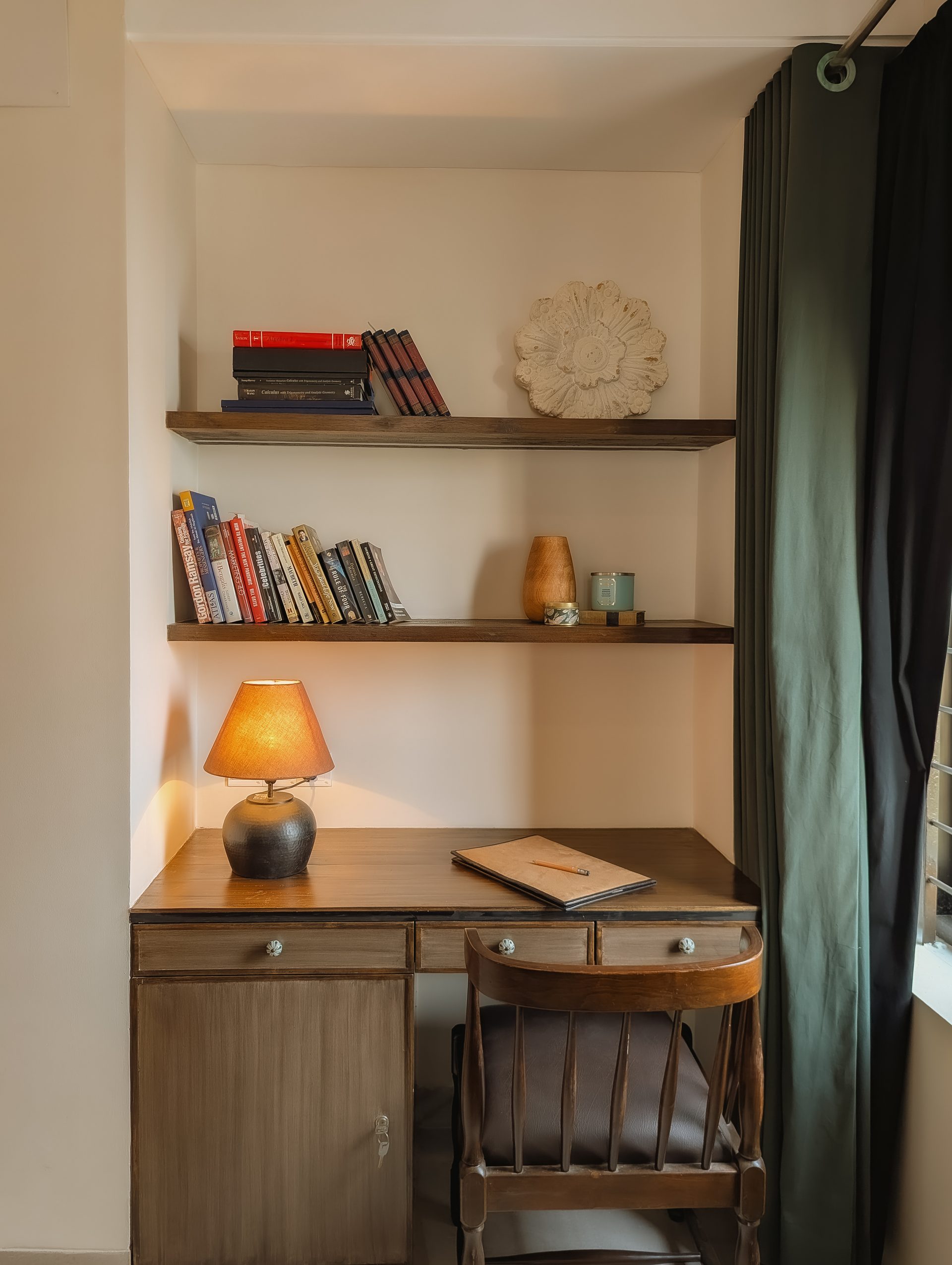 Teak reading desk, shelving and warm table lamp beside the primary bedroom window
