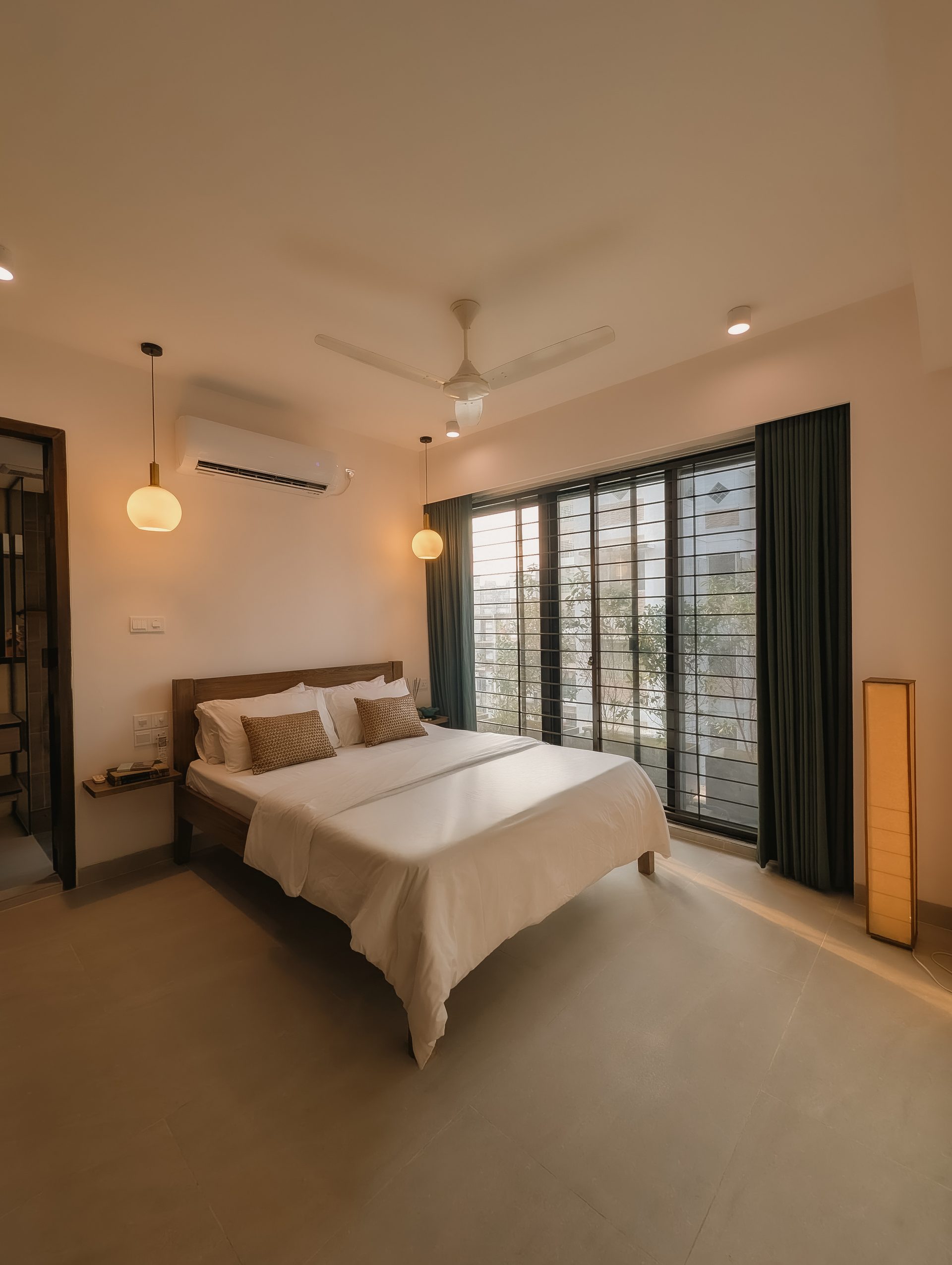 Second bedroom with a teak bed facing broad windows and deep green curtains
