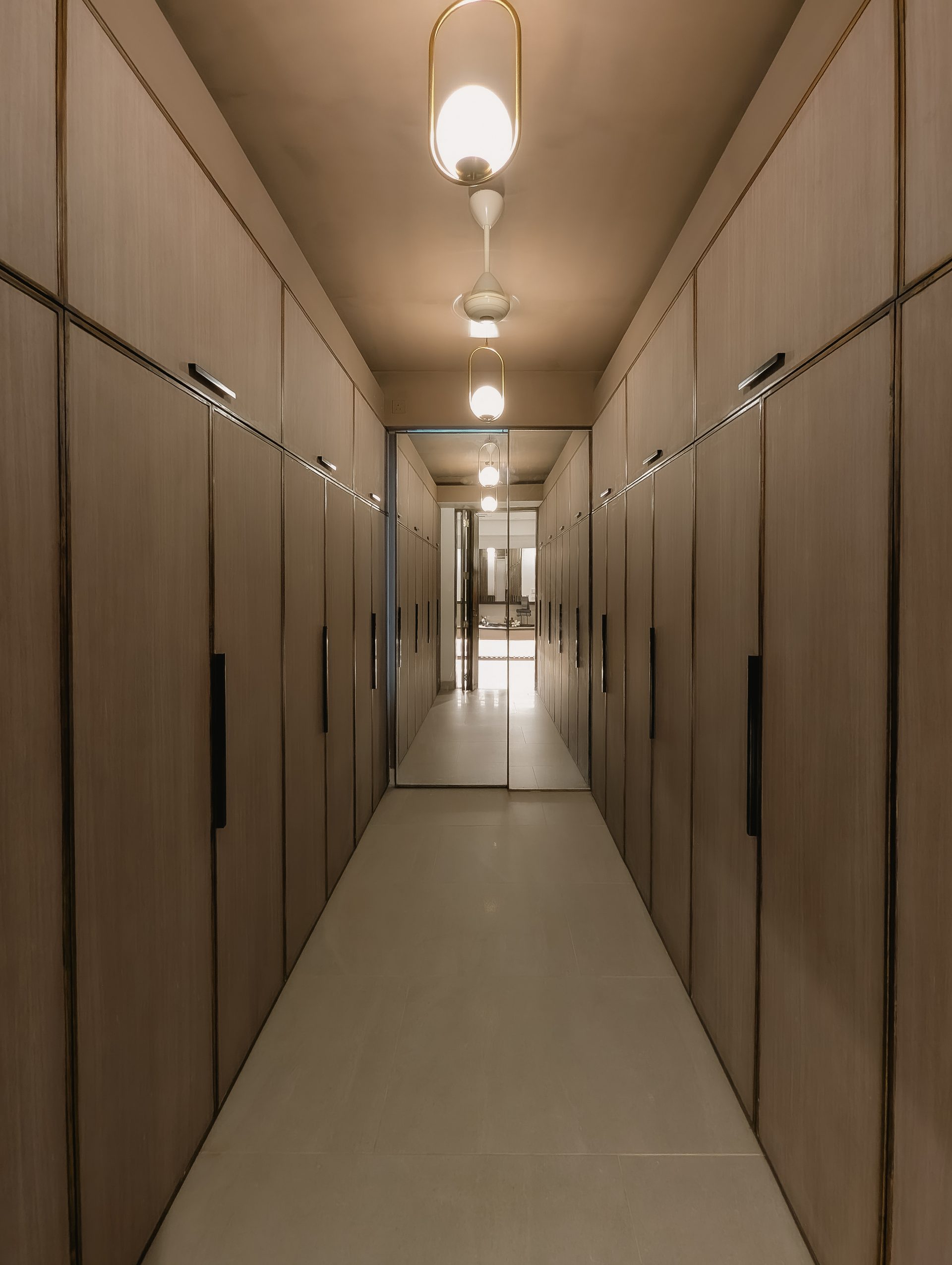 Long walk-in closet with timber cabinetry and a line of pendant lights