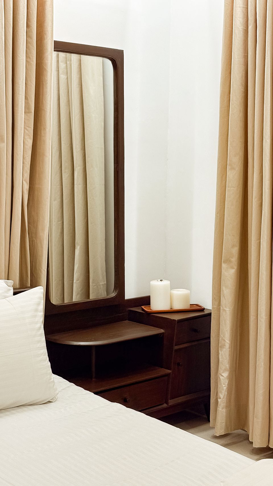 Bedside detail with layered curtains and candlelight