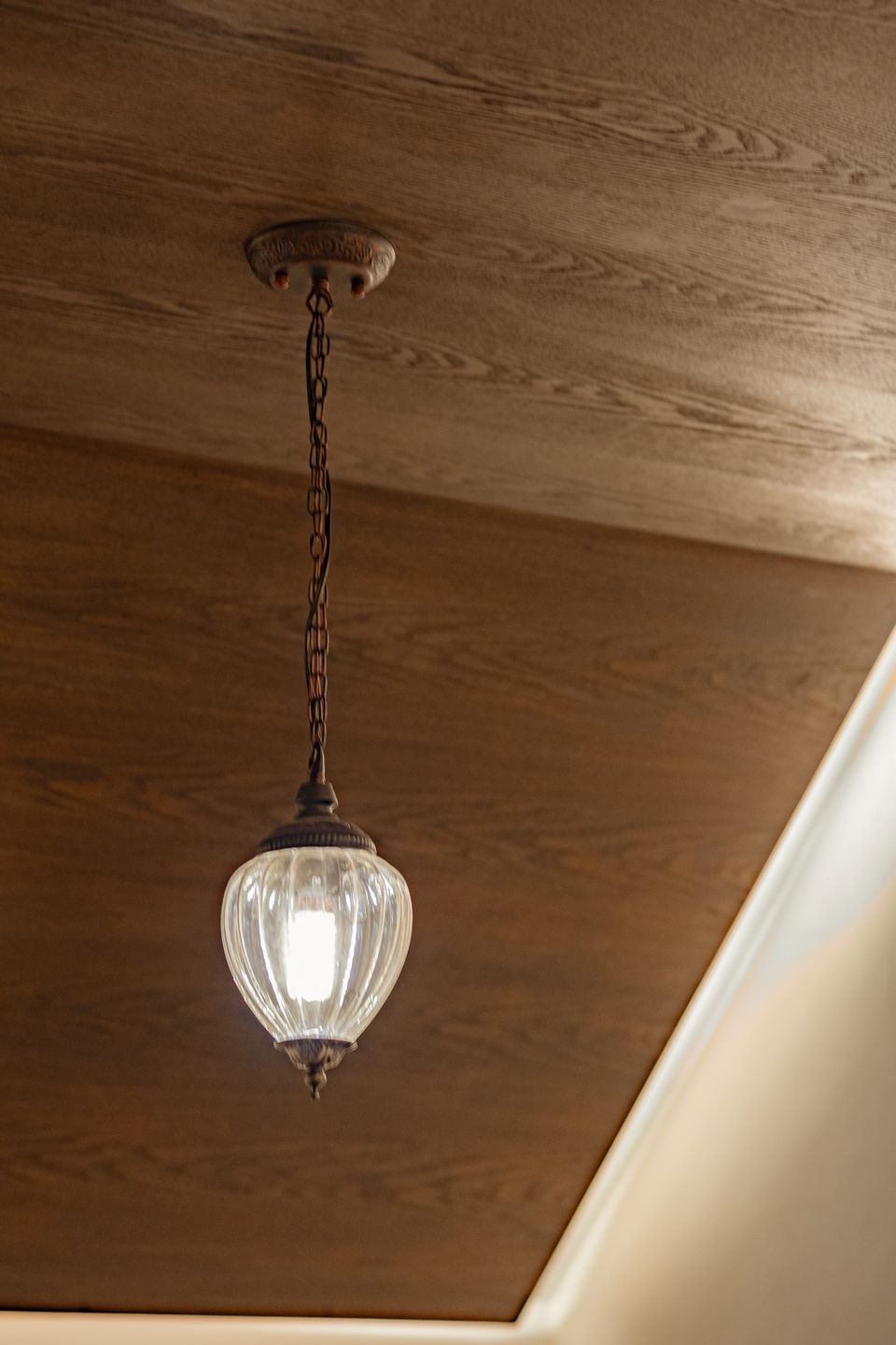 Glass pendant suspended beneath a dark timber ceiling