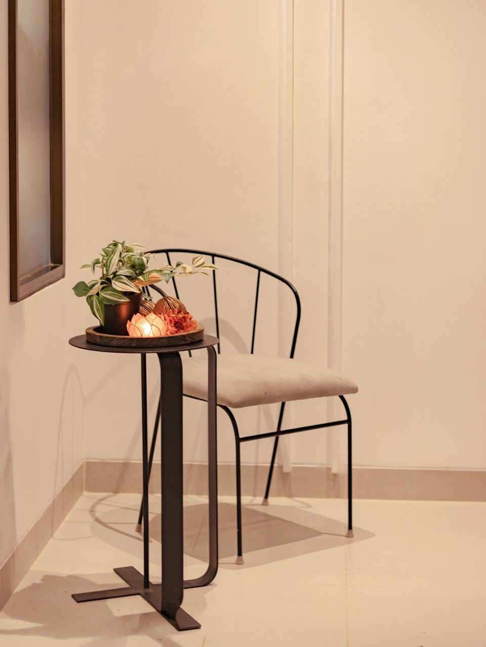 Slim black chair and side table against a pale wall