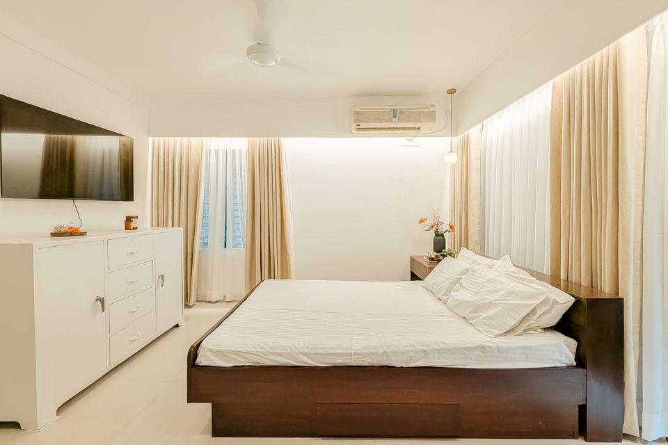 Primary bedroom framed by full-height cream curtains