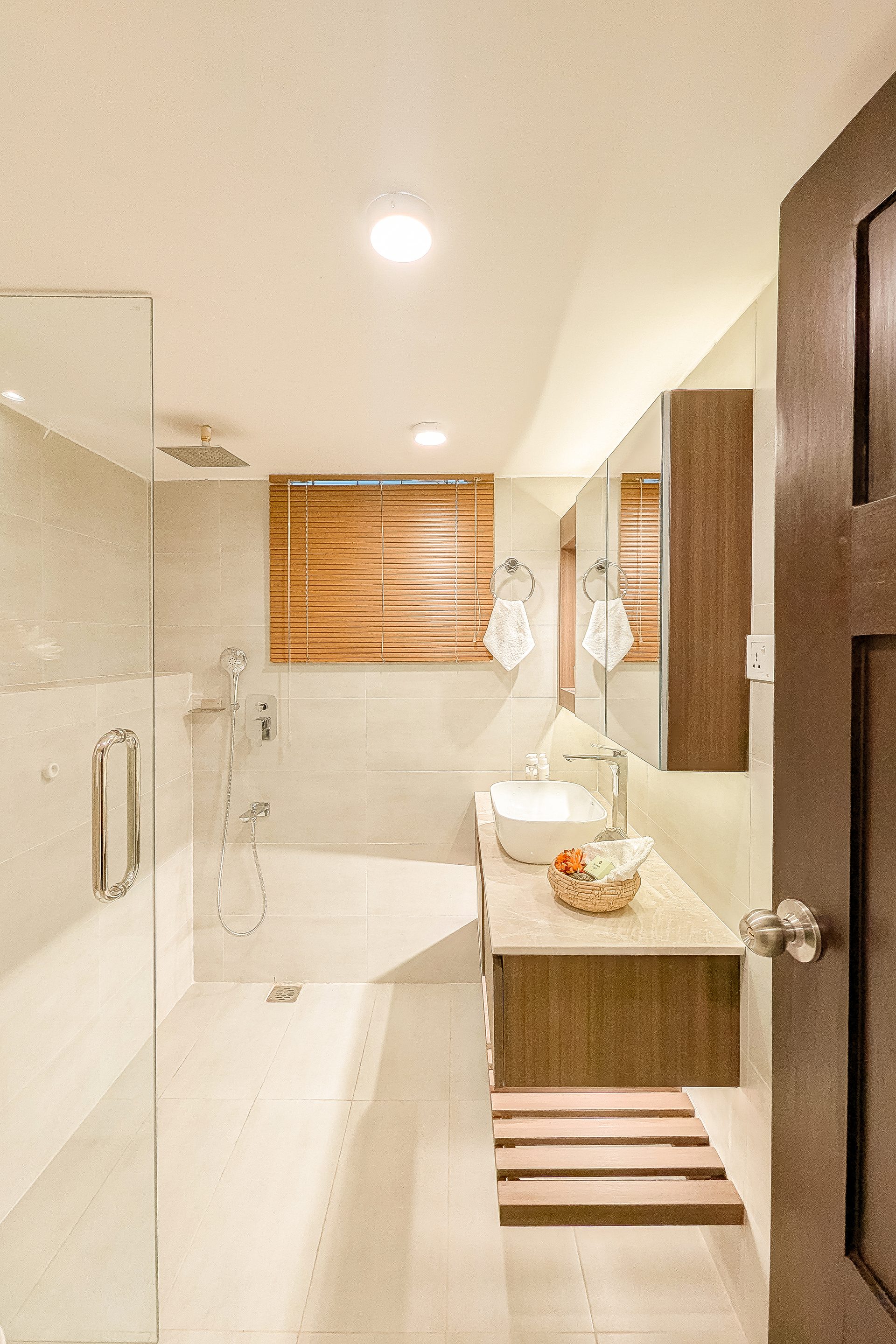 Pale grey bathroom with a timber vanity and glass shower screen