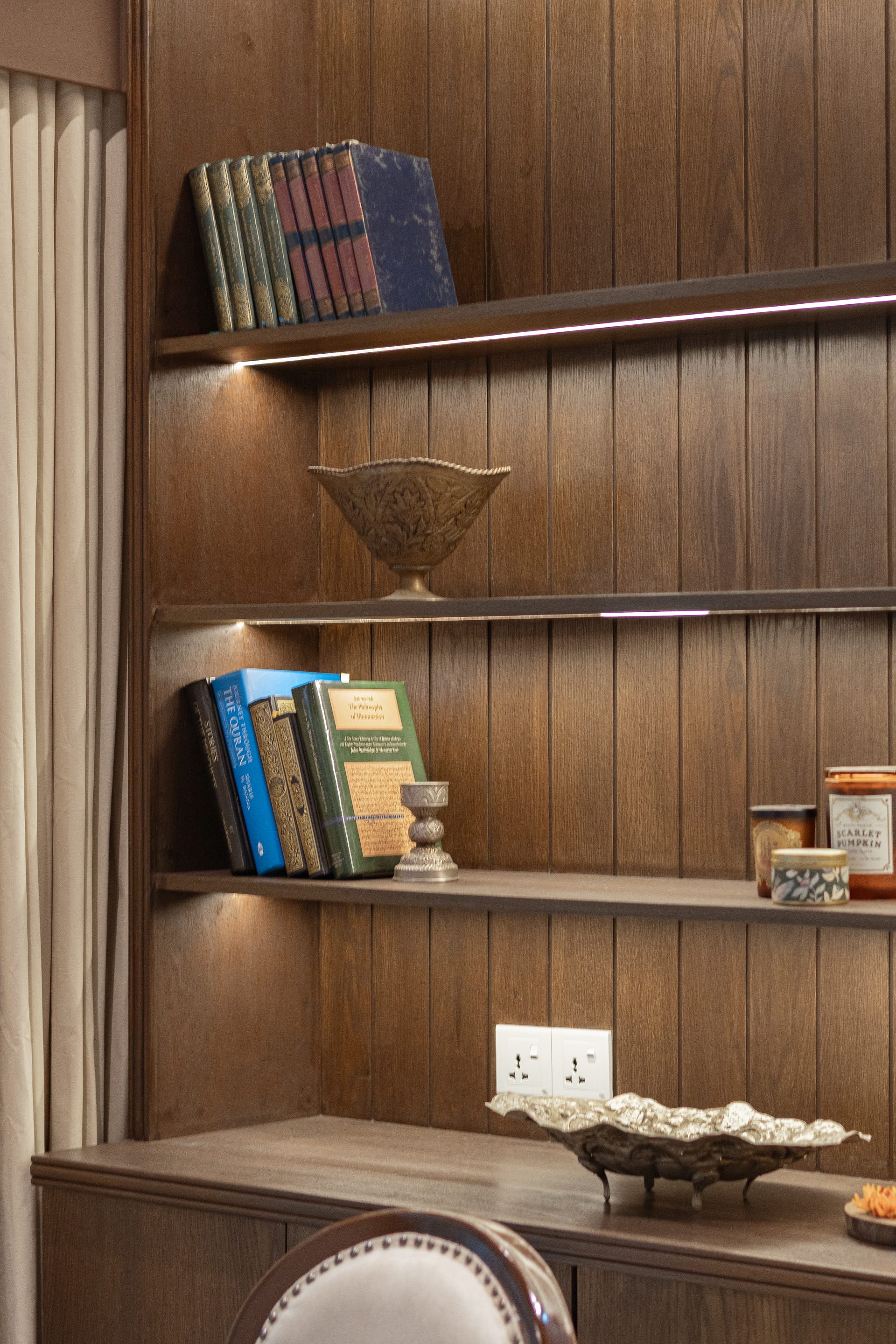 Close view of illuminated timber shelves with books and collected family objects