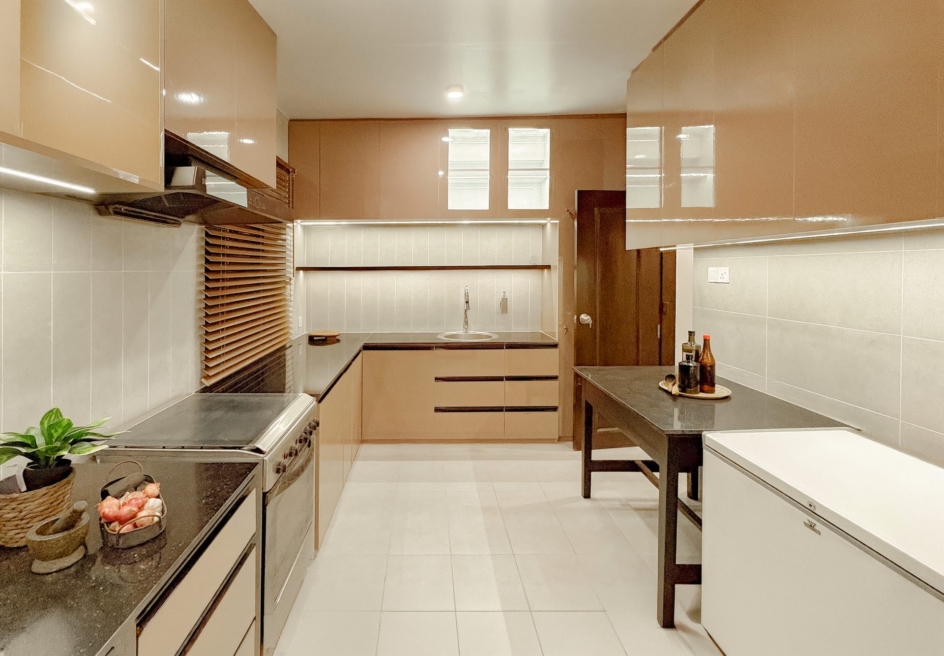 Wide kitchen with warm brown and pale cabinetry arranged around a central work zone