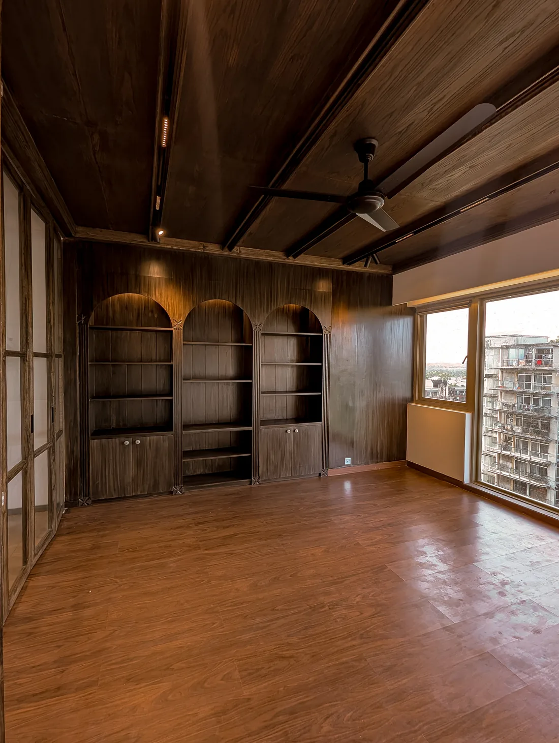 Dark timber arched shelving and a broad city window at Northern Lights Residence